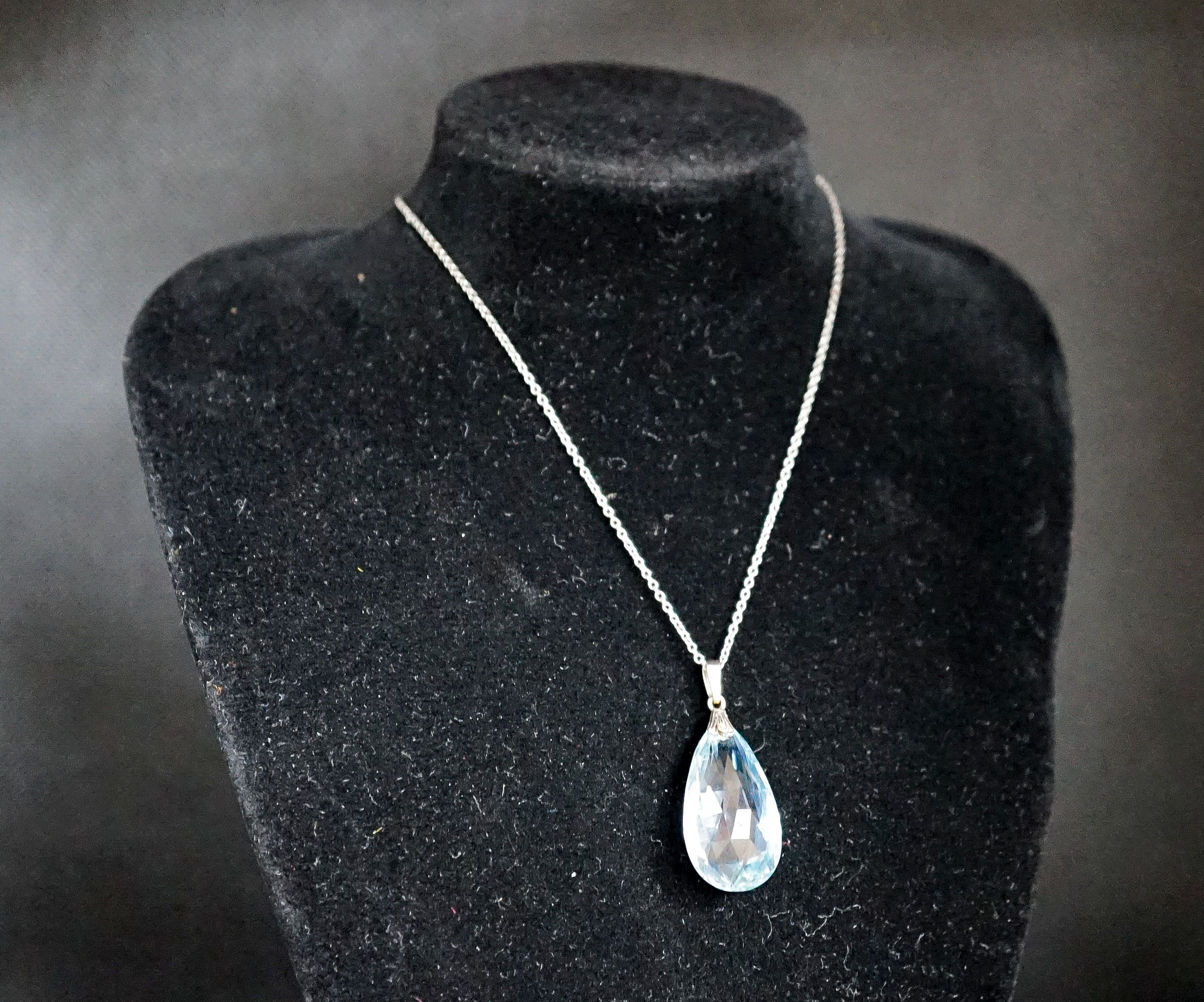 An 18ct mounted facetted pear cut aquamarine set pendant, 33mm, on a 375 white metal fine link chain, 45cm, gross weight 5.2 grams.